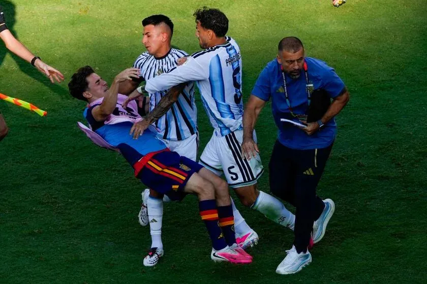 Spain's Gavi, left, falls as he scuffles with Argentina's Leandro Paredes, right, and Thiago Almada during Sunday's match.