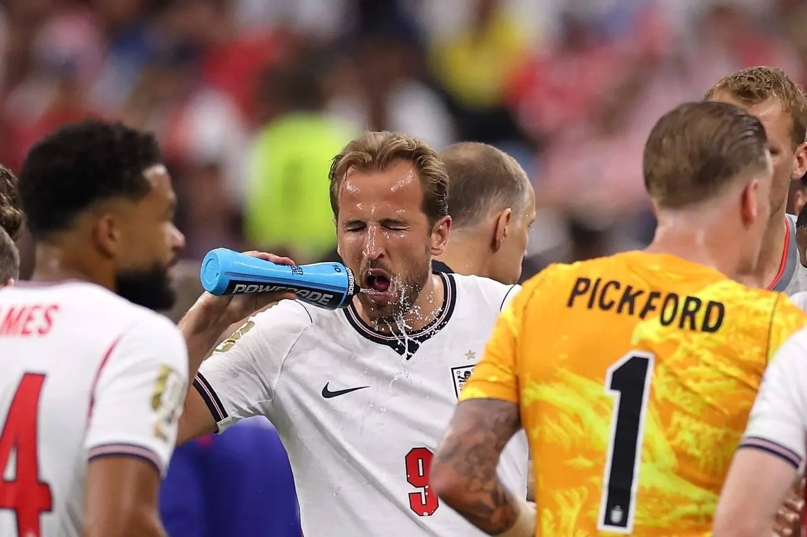 Harry Kane squirts water from a drinking bottle over his face during a break in play